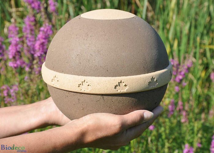 De van organisch compost, zand en mineralen vervaardigde biologisch afbreekbare eco-urn Geos, op handen gedragen.